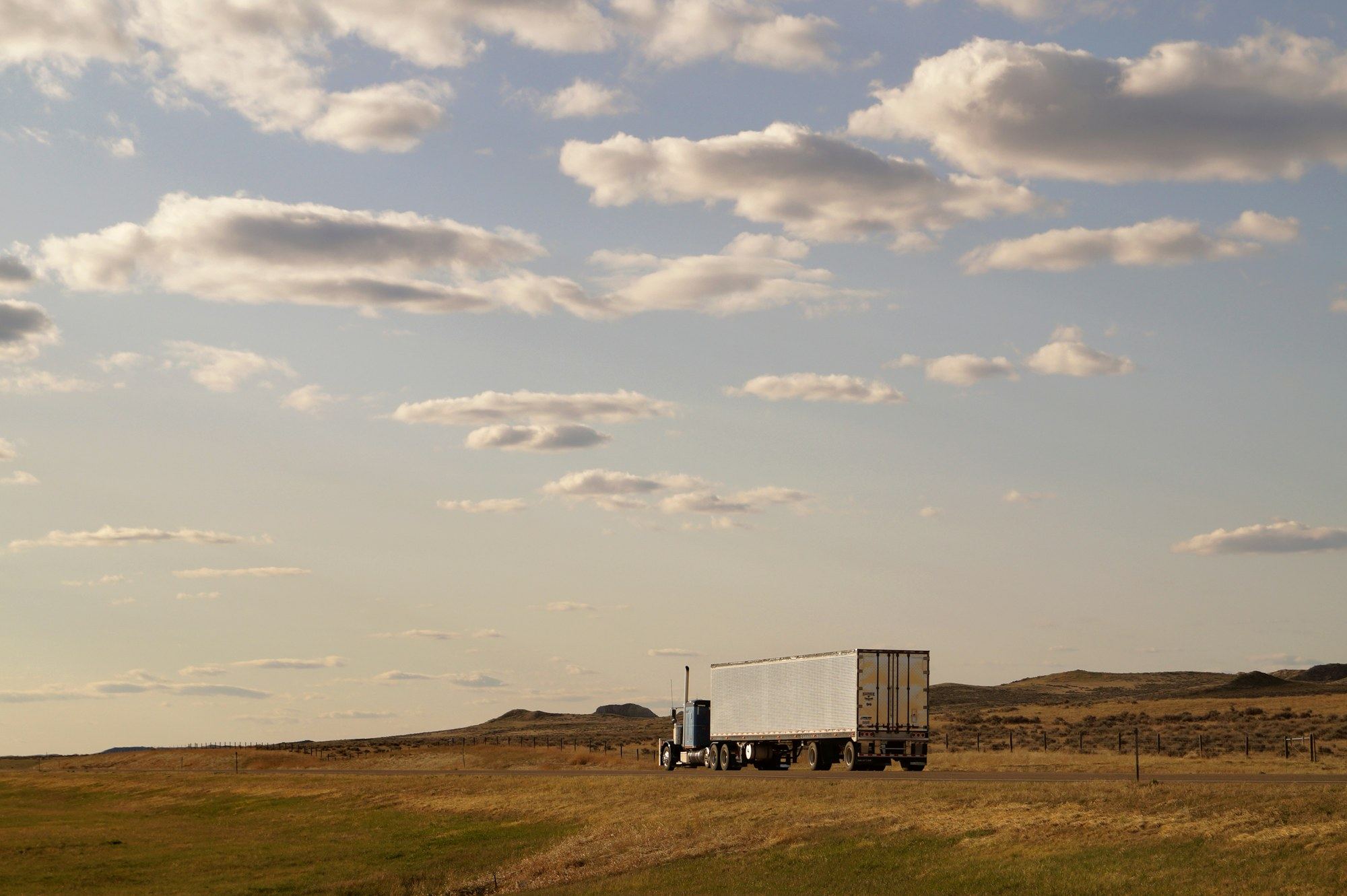 Dry van tractor trailer running an interstate lane at dusk